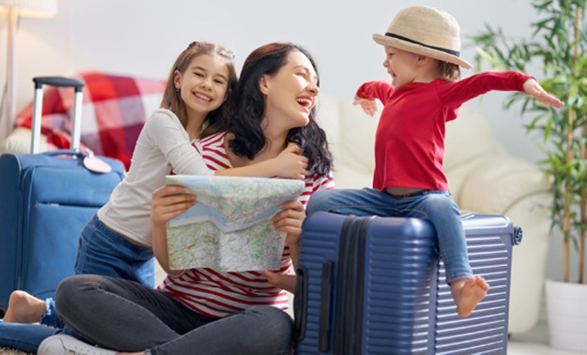 Ratgeber Koffer packen - Mutter packt Koffer mit zwei Kindern